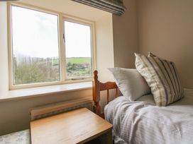 A bedroom with a bed and table next to a window at Orchard Barn Salcombe