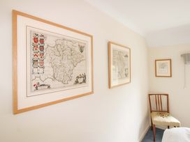 A bedroom with framed maps and a wooden chair at Orchard Barn Salcombe