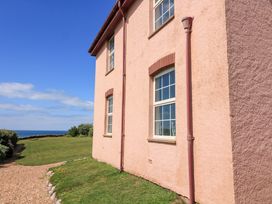 The side of a building with a window and grass at Savernake in Thurlestone