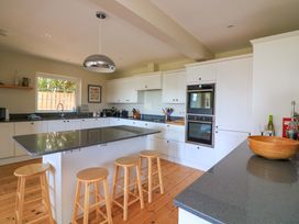 A kitchen with an island and bar stools at Savernake in Thurlestone