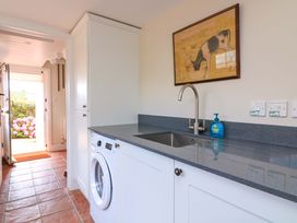 A laundry room with a washing machine and sink at Savernake in Thurlestone