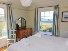 A bedroom with a bed, dresser, and window at Savernake in Thurlestone