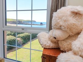 A bedroom with a teddy bear by the window overlooking the ocean at Savernake in Thurlestone