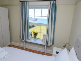 A bedroom with a window overlooking the sea at Savernake in Thurlestone