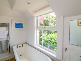 A bathroom with a bath tub and a towel rack at Savernake in Thurlestone