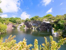 A quarry lake surrounded by cliffs and greenery at Mellydonen Beder Del (Melly), Tor Down Quarry in St Breward