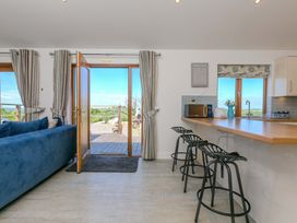 A living room with a sofa and bar stools at Mellydonen Beder Del (Melly), Tor Down Quarry, St Breward