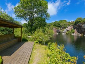A bench by a lake surrounded by greenery at Mellydonen Beder Del (Melly), Tor Down Quarry St Breward