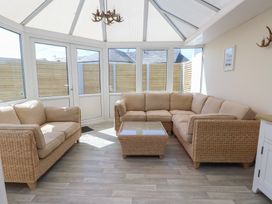 A conservatory with a sofa and coffee table at Maes Y Coed in Morfa Nefyn