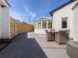 A garden with a conservatory and outdoor furniture at Maes Y Coed in Morfa Nefyn