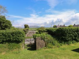 A view of a gate leading to a road among greenery at Maes Y Coed Morfa Nefyn