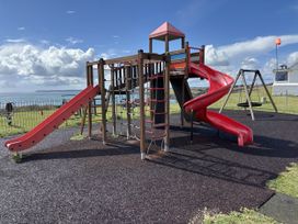 A playground with slides and swings by the sea at Postcard Lodge in Polruan