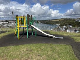 A playground structure with a slide overlooking water at Postcard Lodge in Polruan