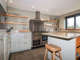 A kitchen with appliances and glasses on shelves at Postcard Lodge Polruan