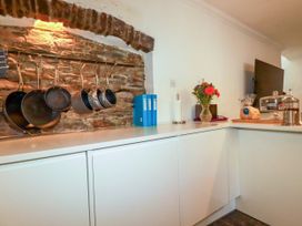 A kitchen with hanging pots and a television at Rock House Trebarwith Strand near Tintagel