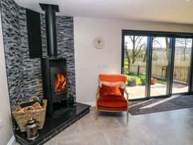 A living room with a wood stove and a chair at The Old Dairy Cotleigh near Honiton