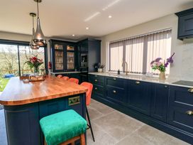 A kitchen with a kitchen island and stools at The Old Dairy Cotleigh near Honiton