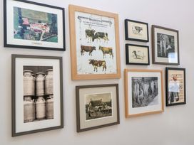 A wall with framed photographs and artworks depicting farming and cows at The Old Dairy in Cotleigh near Honiton