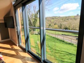 A living room with a large glass door and tv at The Old Dairy Cotleigh near Honiton
