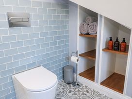 A bathroom with a toilet and shelving at The Old Dairy Cotleigh near Honiton