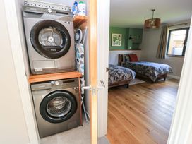 A washing machine and dryer with two beds in a bedroom at The Old Dairy Cotleigh near Honiton