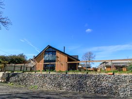 A house with wooden exterior and a garden at The Old Dairy in Cotleigh near Honiton