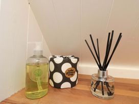 Hand wash, toilet paper, and reed diffuser in a bathroom at Saints Cottage in Scarborough