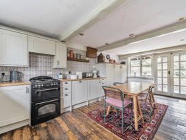 A kitchen with cabinets, stove, table, and chairs at Spring Park Farmhouse in Launceston