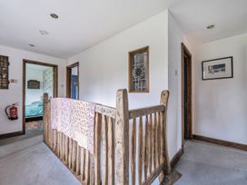 A hallway with a staircase railing and doors at Spring Park Farmhouse in Launceston