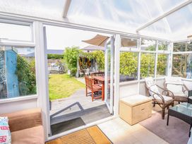 A conservatory leading to a garden with a table and chairs at 32 Cranleigh Close Tuckton