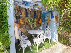 A seating area with white chairs and a table in a decorative outdoor area at 32 Cranleigh Close Tuckton