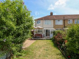 A garden with a house and decking at 32 Cranleigh Close Tuckton