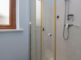 A shower area with a glass door and window at Langtree in Arnside