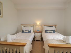 A bedroom with two beds and a bedside table with a lamp at Langtree in Arnside