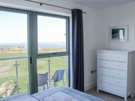 A bedroom with a dresser and a view of the sea at 4 Ocean Reach Bolberry