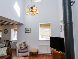 A living room with a chair a television and a chandelier at The Coach House in Lowick near Holy Island