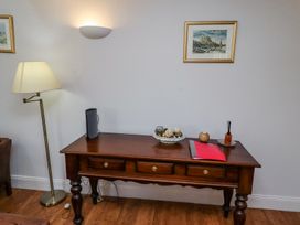 A wooden table with drawers holding a bowl of decorative items a red folder a lamp and framed pictures on the wall at The Coach House in Lowick near Holy Island
