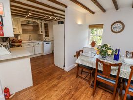 A kitchen and dining area with wooden chairs a table set with plates glasses and flowers and kitchen cabinets with dishes at The Coach House in Lowick near Holy Island