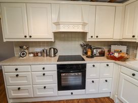 A kitchen with white cabinets and drawers a countertop with a scale jars a kettle a toaster and a basket of bread at The Coach House in Lowick near Holy Island