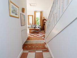 A hallway with a stair railing leading to a living area with a patterned sofa wooden coffee table and window at The Coach House in Lowick near Holy Island