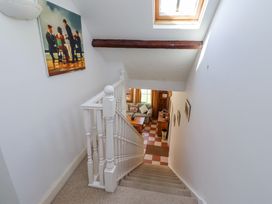 A carpeted staircase with white banisters leading down to a room with a sofa and wooden furniture under a skylight at The Coach House in Lowick near Holy Island