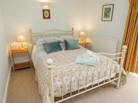 A bedroom with a metal bed frame two bedside tables with lamps and framed pictures on the walls at The Coach House Lowick near Holy Island