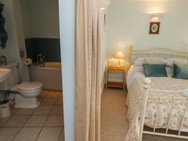 A bedroom with a bed and nightstand next to a bathroom with a toilet and bathtub at The Coach House in Lowick near Holy Island