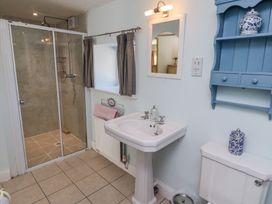 A bathroom with a shower cubicle sink toilet blue wall-mounted cabinet and a window with curtains at The Coach House in Lowick near Holy Island