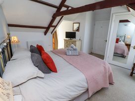 A bedroom with a bed pillows a dresser with a television and a door with a mirror at The Coach House in Lowick near Holy Island