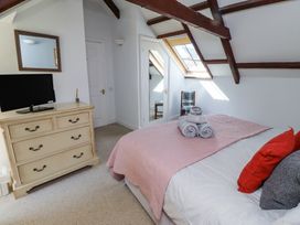 A bedroom with a bed with pillows and towels dresser with a TV mirror on the wall and a skylight window at The Coach House in Lowick near Holy Island