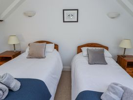 A bedroom with two single beds each with a pillow and a bedside table with a lamp at The Coach House in Lowick near Holy Island
