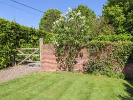 A garden with grass a wooden gate a brick wall and trees at The Coach House in Lowick near Holy Island