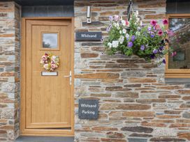 A front entrance with a wooden door and flower basket at Whitsand in Tideford