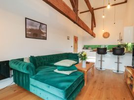 A living room with a green sofa and a kitchen area at Repton @ Engine Shed in Whitby